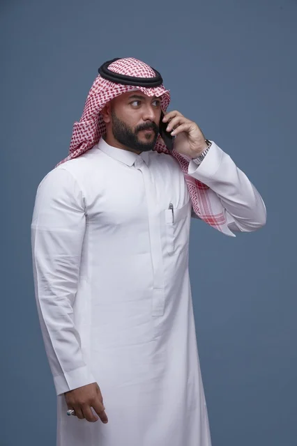 Saudi Man in Traditional Thobe Talking on Smartphone
