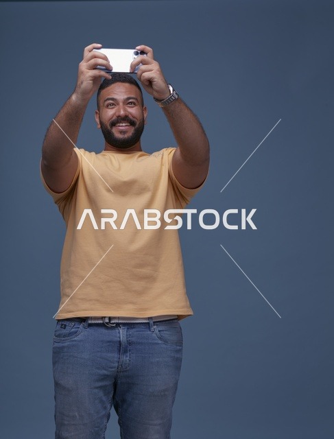 شاب سعودي بملابس كاجوال يستخدم هاتف ذكي