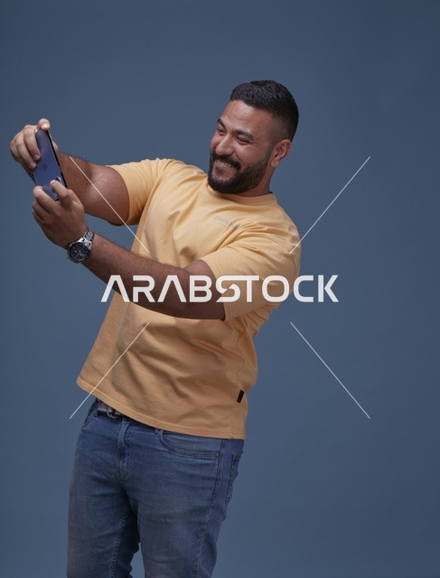 رجل سعودي مبتسم يستخدم الهاتف الذكي في الاستوديو