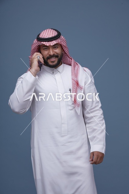 رجل سعودي مبتسم يتحدث بالهاتف الذكي تصوير استوديو