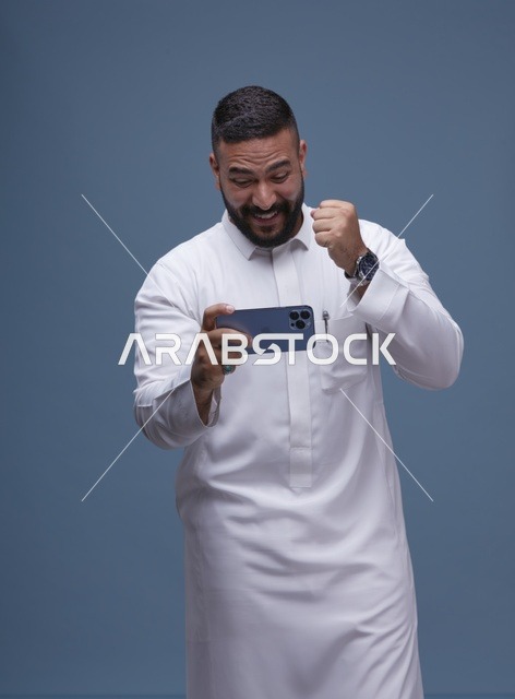 رجل سعودي يلعب بهاتفه الذكي ويحتفل بالفوز