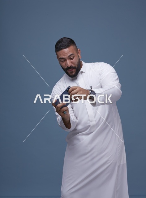 رجل سعودي يستخدم الهاتف الذكي للألعاب المحمولة في استوديو