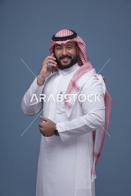 رجل سعودي مبتسم يتحدث بالهاتف في الاستوديو