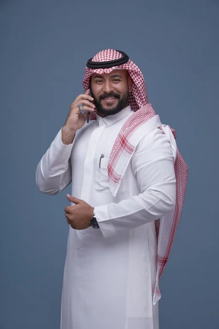 رجل سعودي مبتسم يتحدث بالهاتف في الاستوديو