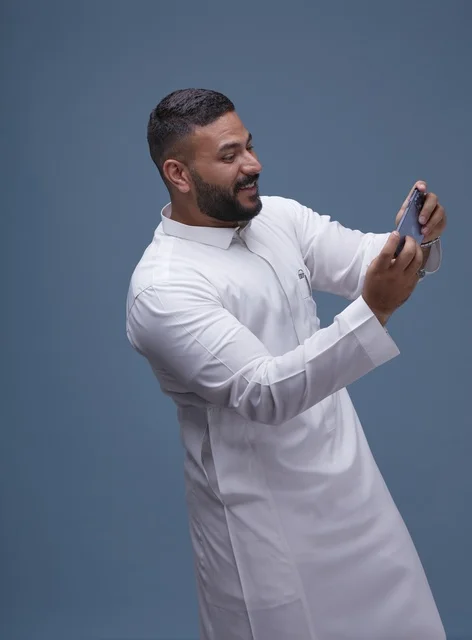Saudi Man in Thobe Using Smartphone for Gaming