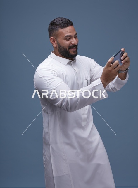 رجل سعودي يستخدم الهاتف الذكي للألعاب المحمولة في الاستوديو