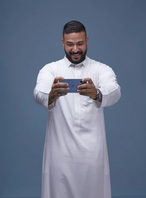 Saudi Man in Thobe Playing Mobile Game on Smartphone