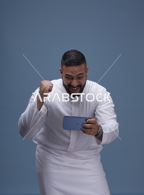 رجل سعودي يلعب ألعاب الجوال على الهاتف الذكي