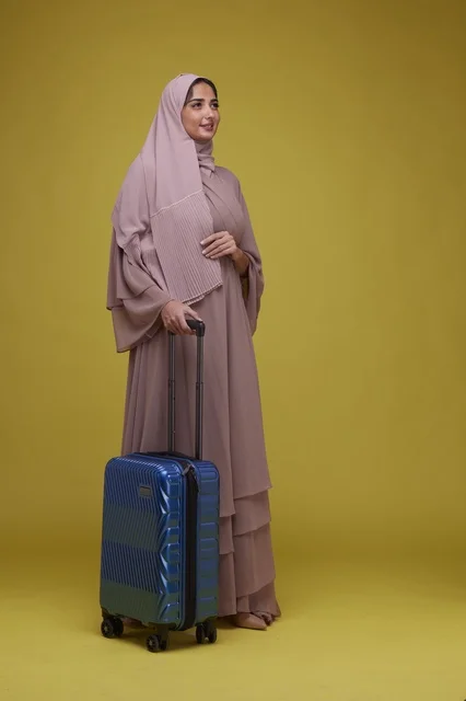 Saudi Woman with Blue Suitcase on Yellow Background Saudi Woman with Blue Suitcase on Yellow Background