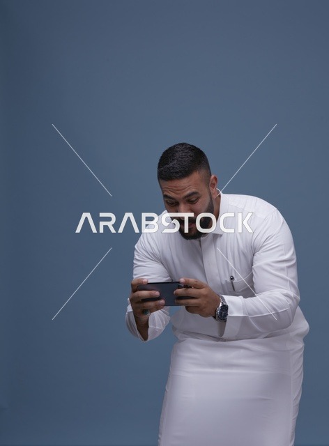 رجل سعودي يلعب ألعاب الجوال على الهاتف الذكي
