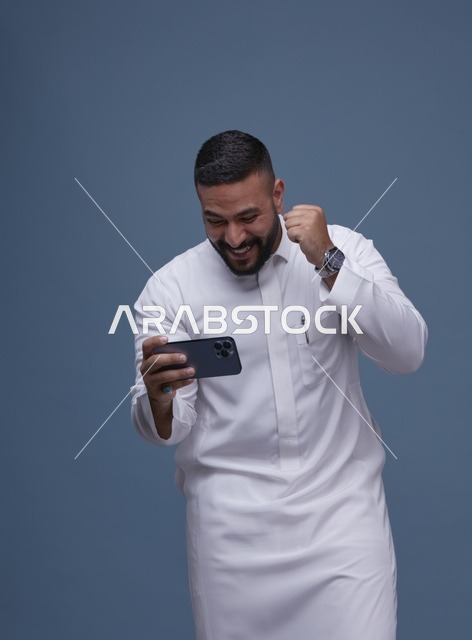 رجل سعودي يستخدم الهاتف الذكي للألعاب المحمولة في استوديو