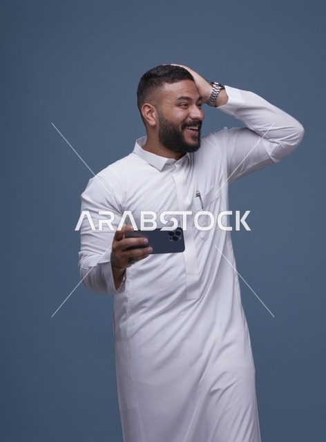رجل سعودي يحمل هاتف ذكي بتعبير مفاجأة ونجاح