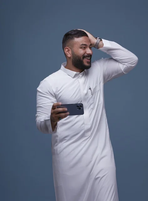رجل سعودي يحمل هاتف ذكي بتعبير مفاجأة ونجاح