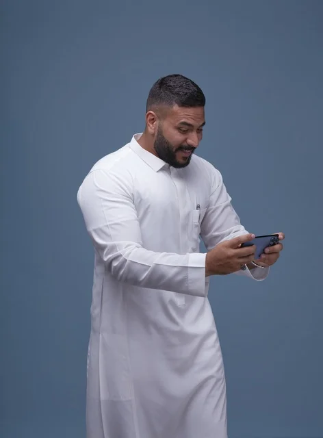 Saudi Man in Thobe Using Smartphone for Mobile Gaming