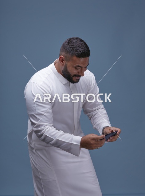 رجل سعودي يستخدم الهاتف الذكي للألعاب المحمولة