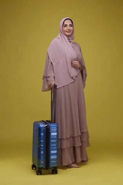 امرأة سعودية مع حقيبة سفر على خلفية صفراء امرأة سعودية مع حقيبة سفر على خلفية صفراء