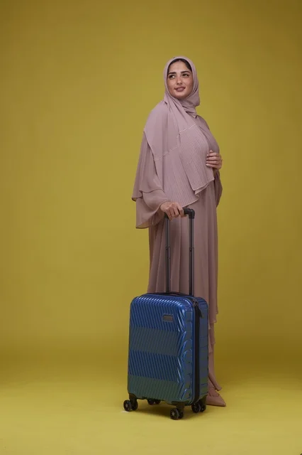 امرأة سعودية مع حقيبة سفر زرقاء خلفية صفراء