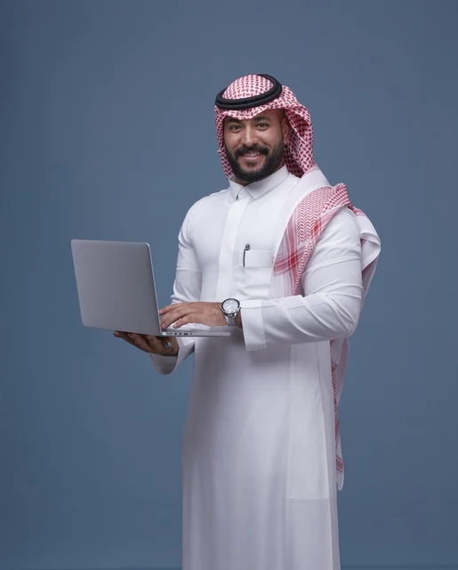 رجل أعمال سعودي يحمل حاسوب محمول بالزي التقليدي