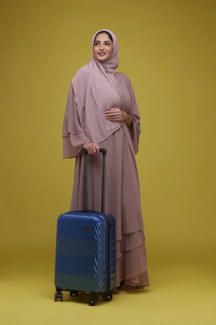 امرأة سعودية مع حقيبة سفر على خلفية صفراء