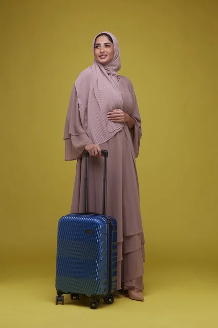 Saudi Woman with Blue Suitcase on Yellow Background Saudi Woman with Blue Suitcase on Yellow Background