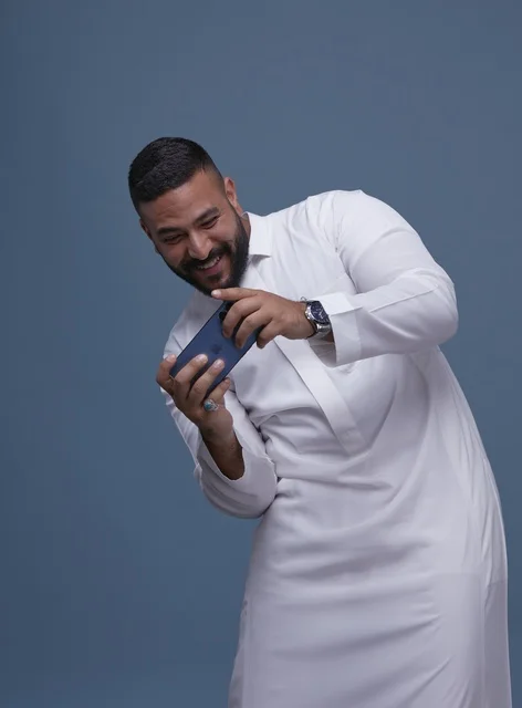 رجل سعودي يلعب ألعاب المحمول على الهاتف الذكي