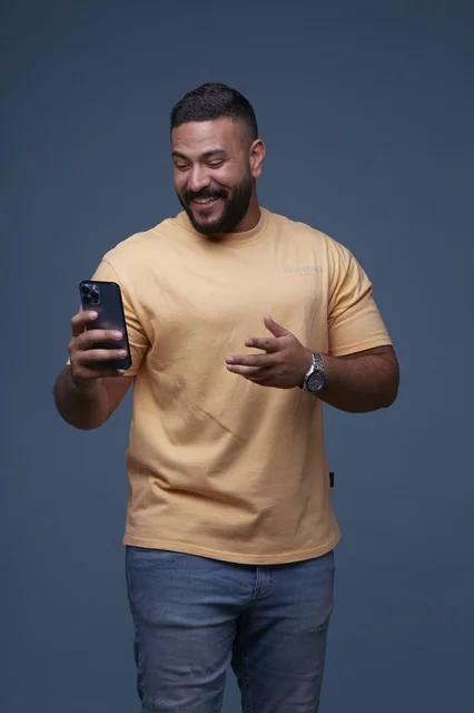 Smiling Saudi Man Using Smartphone in Casual Studio Shot