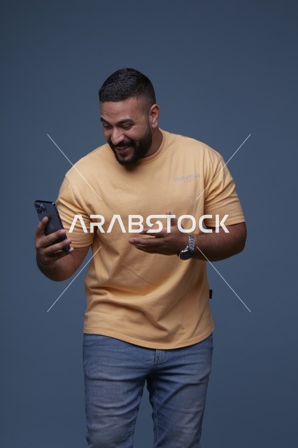 رجل سعودي يستخدم الهاتف الذكي بملابس كاجوال