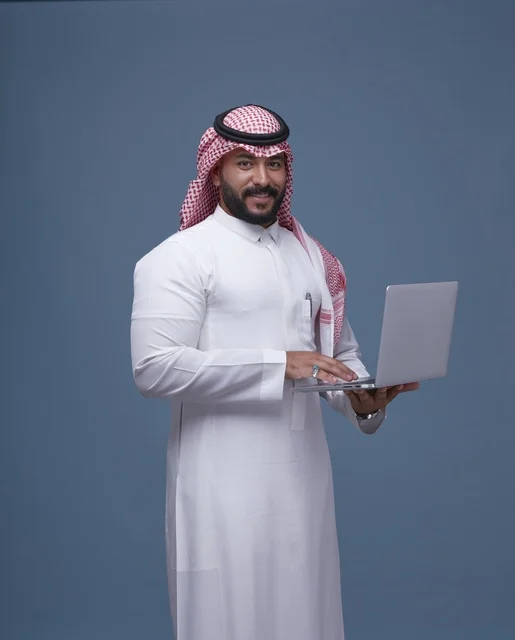 رجل أعمال سعودي يستخدم الحاسوب المحمول بالزي التقليدي