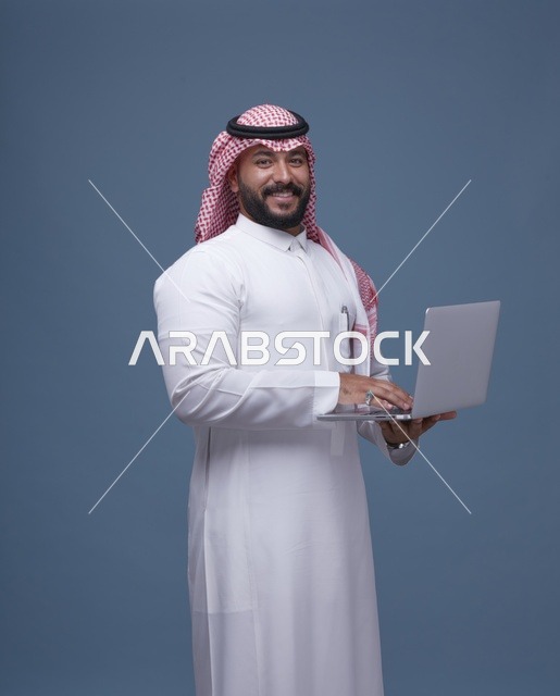 رجل أعمال سعودي يستخدم الحاسوب المحمول بالزي التقليدي