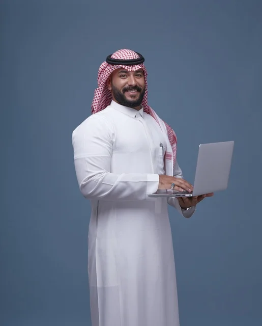 رجل أعمال سعودي يستخدم الحاسوب المحمول بالزي التقليدي