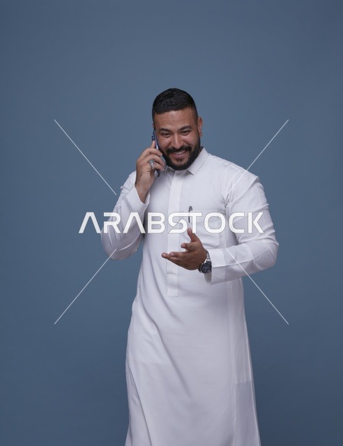 رجل سعودي بالثوب الأبيض يتحدث بالهاتف الذكي
