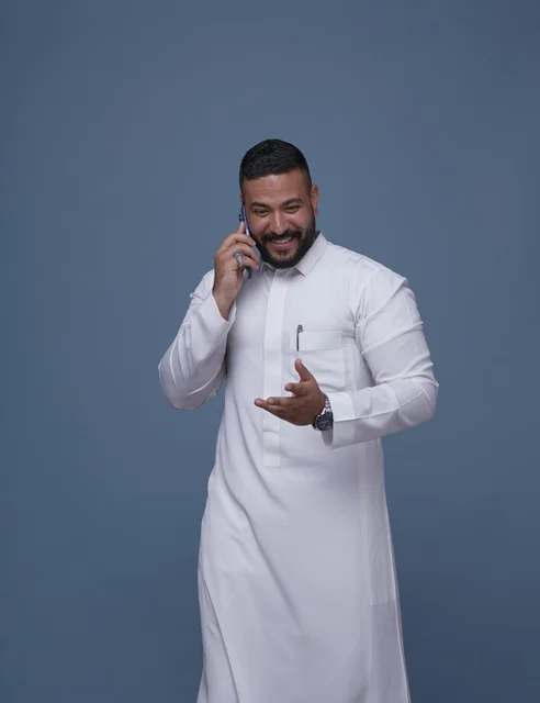 رجل سعودي بالثوب الأبيض يتحدث بالهاتف الذكي