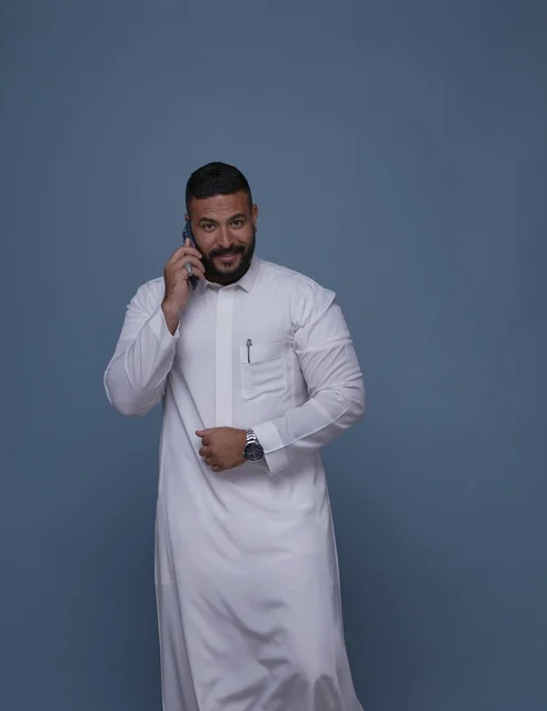 Saudi Man in White Thobe Talking on Smartphone
