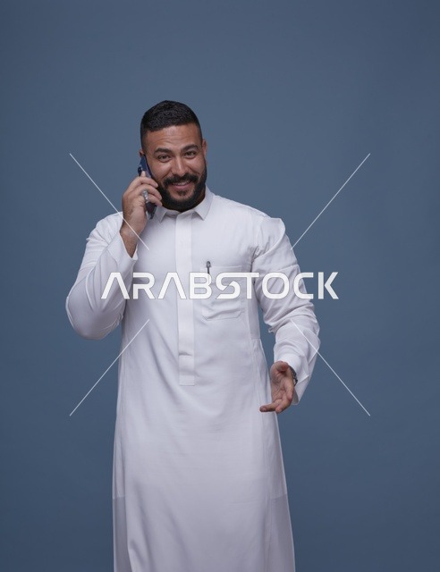 رجل سعودي بالثوب الأبيض يتحدث عبر الهاتف الذكي