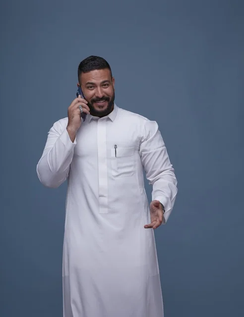 رجل سعودي بالثوب الأبيض يتحدث عبر الهاتف الذكي