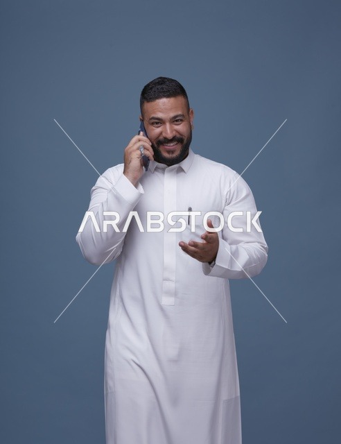 رجل سعودي بالثوب الأبيض يتحدث عبر الهاتف الذكي