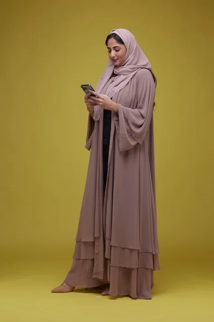 امرأة سعودية بالعباءة تستخدم الهاتف الذكي في الاستوديو