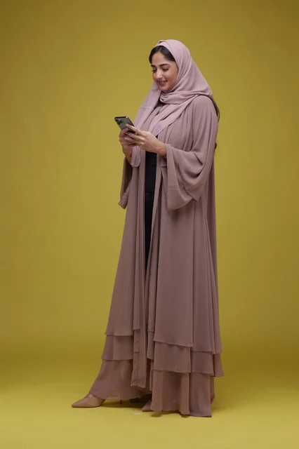 امرأة سعودية تستخدم الجوال في استوديو خلفية صفراء