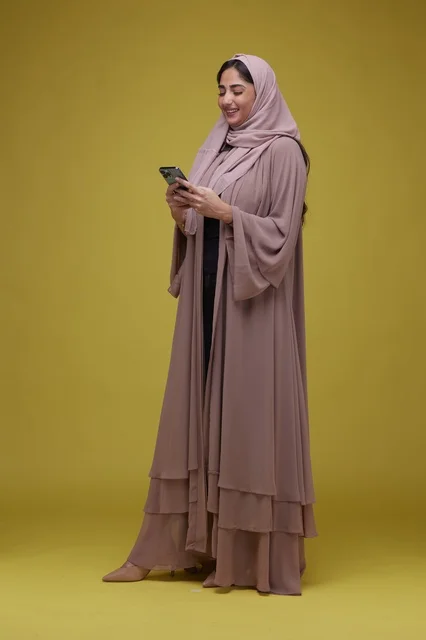 Saudi Woman Using Smartphone on Yellow Studio Background