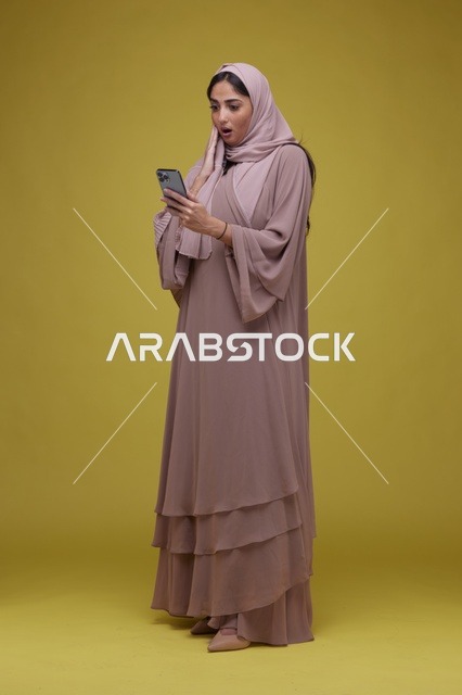 امرأة سعودية تستخدم الهاتف الذكي بتعبير متفاجئ