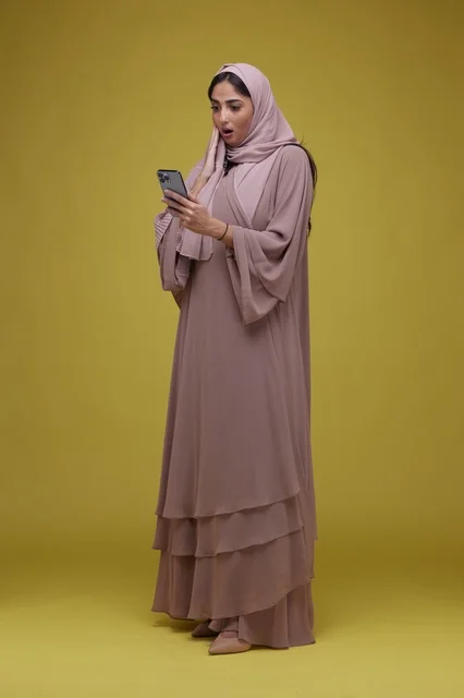 امرأة سعودية تستخدم الهاتف الذكي بتعبير متفاجئ