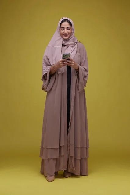 Saudi Woman Using Smartphone on Yellow Studio Background