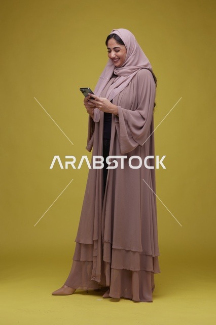 امرأة سعودية تستخدم الهاتف الذكي بخلفية صفراء