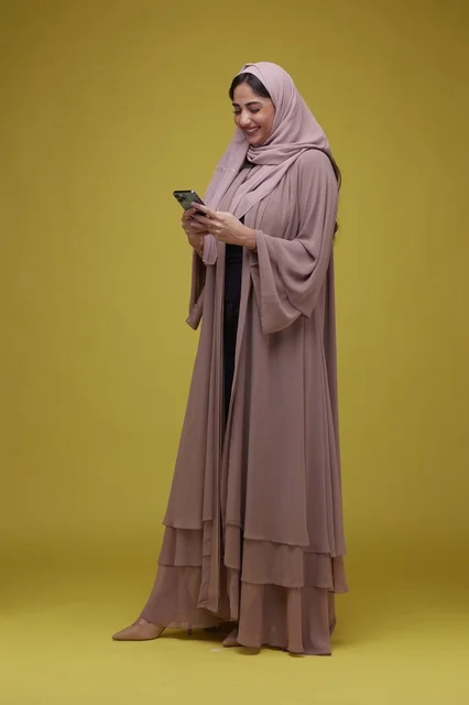 امرأة سعودية تستخدم الهاتف الذكي بخلفية صفراء