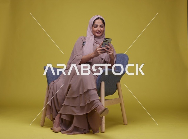 امرأة سعودية تستخدم الهاتف الذكي على خلفية صفراء