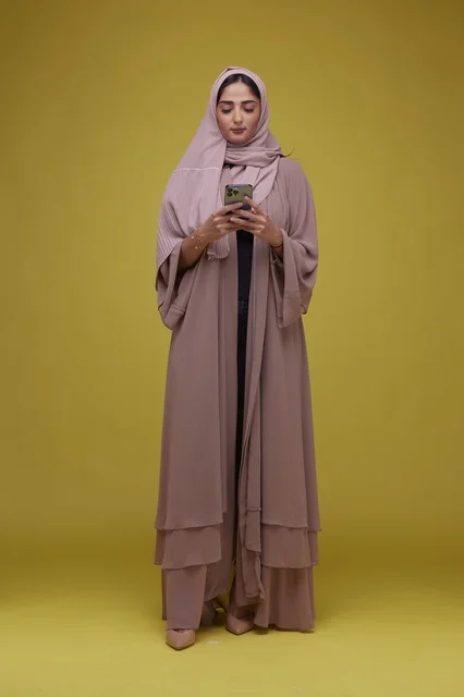 امرأة سعودية بعباية تستخدم هاتف ذكي في استوديو