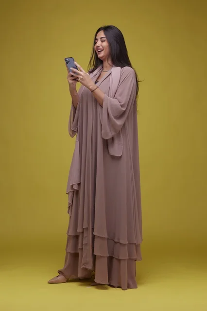 Saudi Woman Using Smartphone on Yellow Background