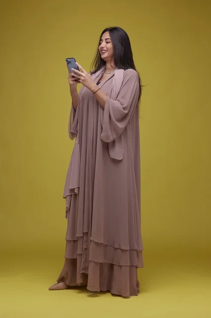 Saudi Woman Using Smartphone on Yellow Studio Background
