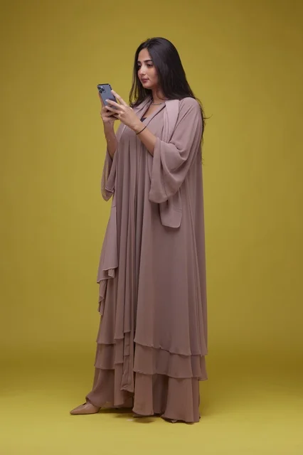 Saudi Woman Using Smartphone on Yellow Background