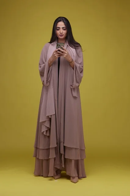 Saudi Woman Using Smartphone on Yellow Background
